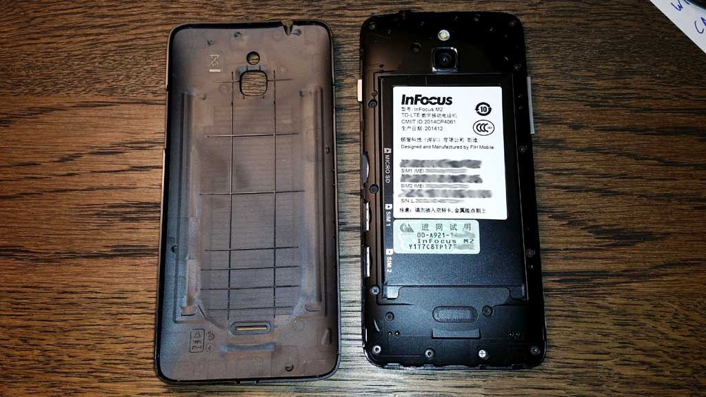 Батарейный отсек телефона InFocus M2. Видна наклейка на батарее, акцизная марка, слоты для SIM-карт и карты памяти.